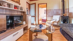 Una sala de estar moderna con televisión, una mesa de centro de vidrio, un sofá y una chimenea.
