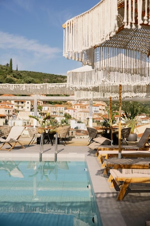Una piscina al aire libre, sombrillas, sillones reclinables de piscina