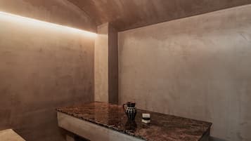 A bathroom with a marble countertop, a decorative vase, and a small container.