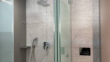 Un baño moderno con cabina de ducha de vidrio, inodoro y pared con diseño.