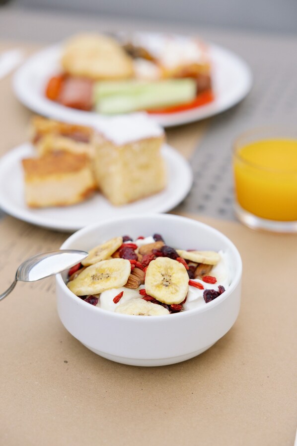 A breakfast setting with a bowl of cereal, a plate with toast, and a glass of orange juice. - Las Hotel & Spa (East Mani)