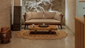 A modern interior with a large textured wall, a wooden bench, and a cushioned sofa.