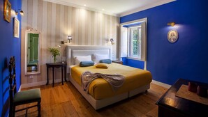 A bedroom with a large bed, a bedside table, a chair, a mirror, and a window. - Palácio de Sintra Boutique House (Sintra)