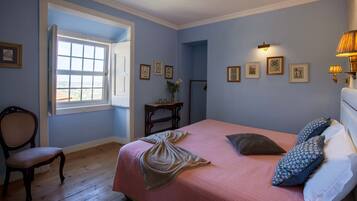 A bedroom with a bed, a chair, a desk, and a window.