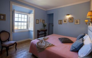 Un dormitorio con una cama, una silla, un escritorio y una ventana.