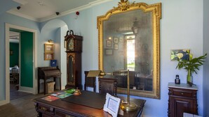 A room with a large ornate mirror, a wooden desk with a telephone, and a clock. - Palácio de Sintra Boutique House (Sintra)