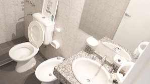 A bathroom with two toilets, a sink, and a shower. - Buda Apartments (San Rafael)