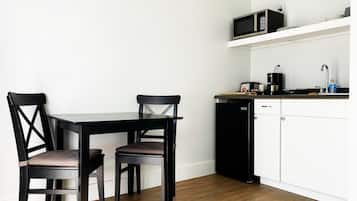 Een praktische keuken met een eettafel en stoelen, een magnetron, een koffiezetapparaat en een vaatwasser.