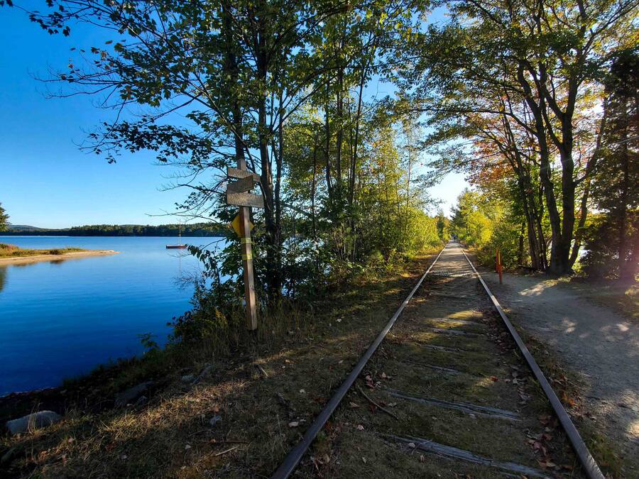 Une voie ferrée avec un panneau indicateur en bois indiquant les directions vers différents lieux.