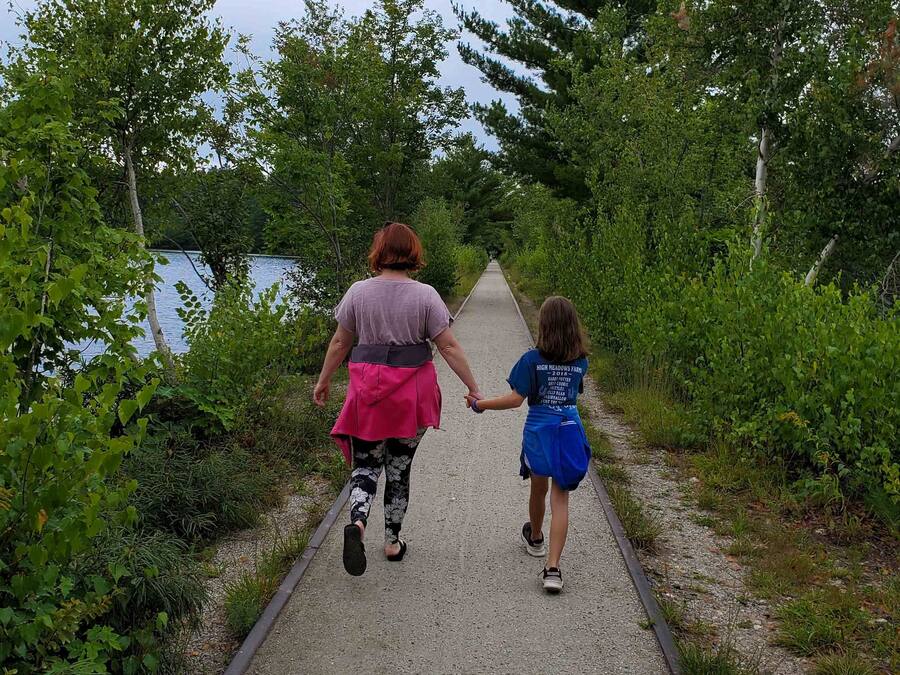 A pathway flanked by greenery and a body of water.