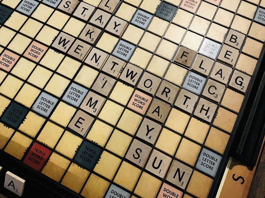 Un tablero de Scrabble con fichas dispuestas en una cuadrícula, cada una con una letra y un valor numérico.