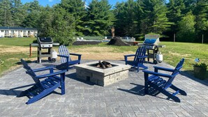 Een terras met Adirondack-stoelen, een vuurkorf en barbecues.