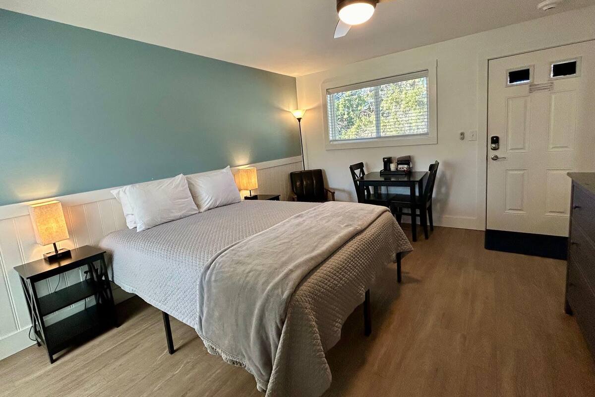 A bedroom with a bed, bedside tables, a desk, and a chair.