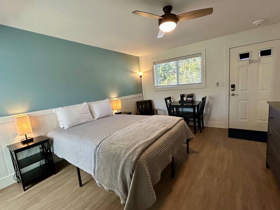 Quarto com cama, mesas de cabeceira, escrivaninha e cadeira.