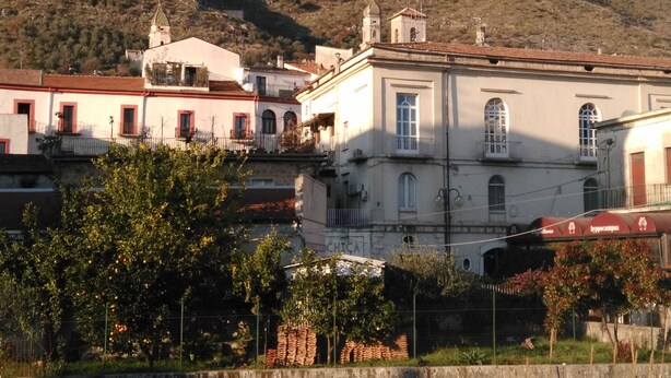 Un edificio de fachada blanca, con varias ventanas y una torre campanario.