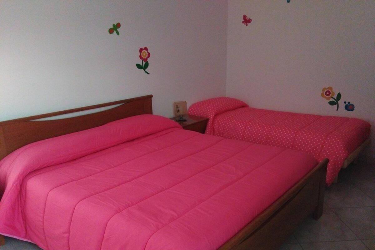 Une chambre avec deux lits, une tête de lit en bois, une table de chevet et un mur décoré de motifs floraux.