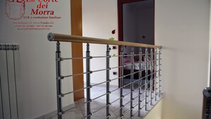 Barandilla de metal con pasamanos de madera, suelo de baldosas y pared con un letrero comercial.