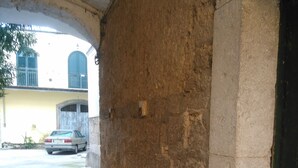 Un sendero adoquinado que lleva a un edificio con un muro de piedra y una puerta verde.