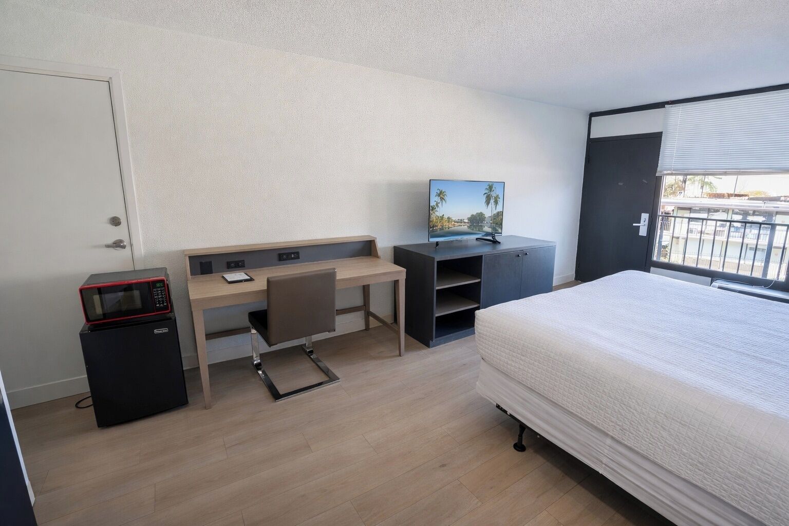Une chambre d’hôtel équipée d’un lit, d’un bureau avec une chaise, d’une télévision et d’un four à micro-ondes.