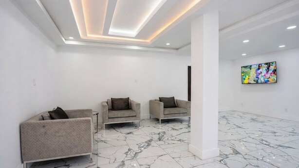 A spacious room with a marble floor, three sofas, a large TV, and a ceiling with recessed lighting. - 1st Place Hotel Decatur I-20 East Atlanta (Decatur)