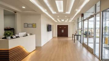 A reception area with a wooden bench, a reception desk, framed certificates on the wall, and a large window offering a view outside.