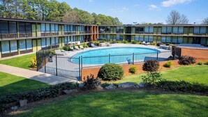 A modern hotel with a central swimming pool, surrounded by a brick wall and a metal fence. - 1st Place Hotel Decatur I-20 East Atlanta (Decatur)