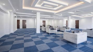 A spacious hotel lobby with a checkered carpet, seating area with sofas, and a modern ceiling design.