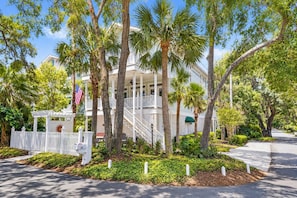 A two-story building with a white exterior, a covered porch, and a flag. - A Summer Hour Retreat, Pet-Friendly, Walk to the Village (Saint Simons Island)