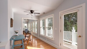 A bright room with wooden floors, a ceiling fan, and a door leading to a balcony.