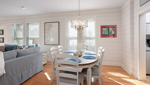 A dining area with a white table and chairs, a chandelier, and a map on the wall.
