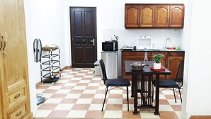 Een kleine keuken met een magnetron, spoelbak en houten kastjes.