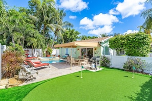 A backyard with a swimming pool, patio furniture, and a lawn.