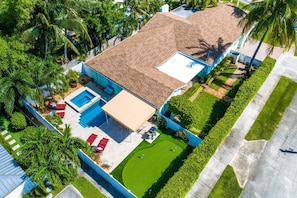 An aerial view of a residential property with a swimming pool, patio area, and well-maintained lawn.