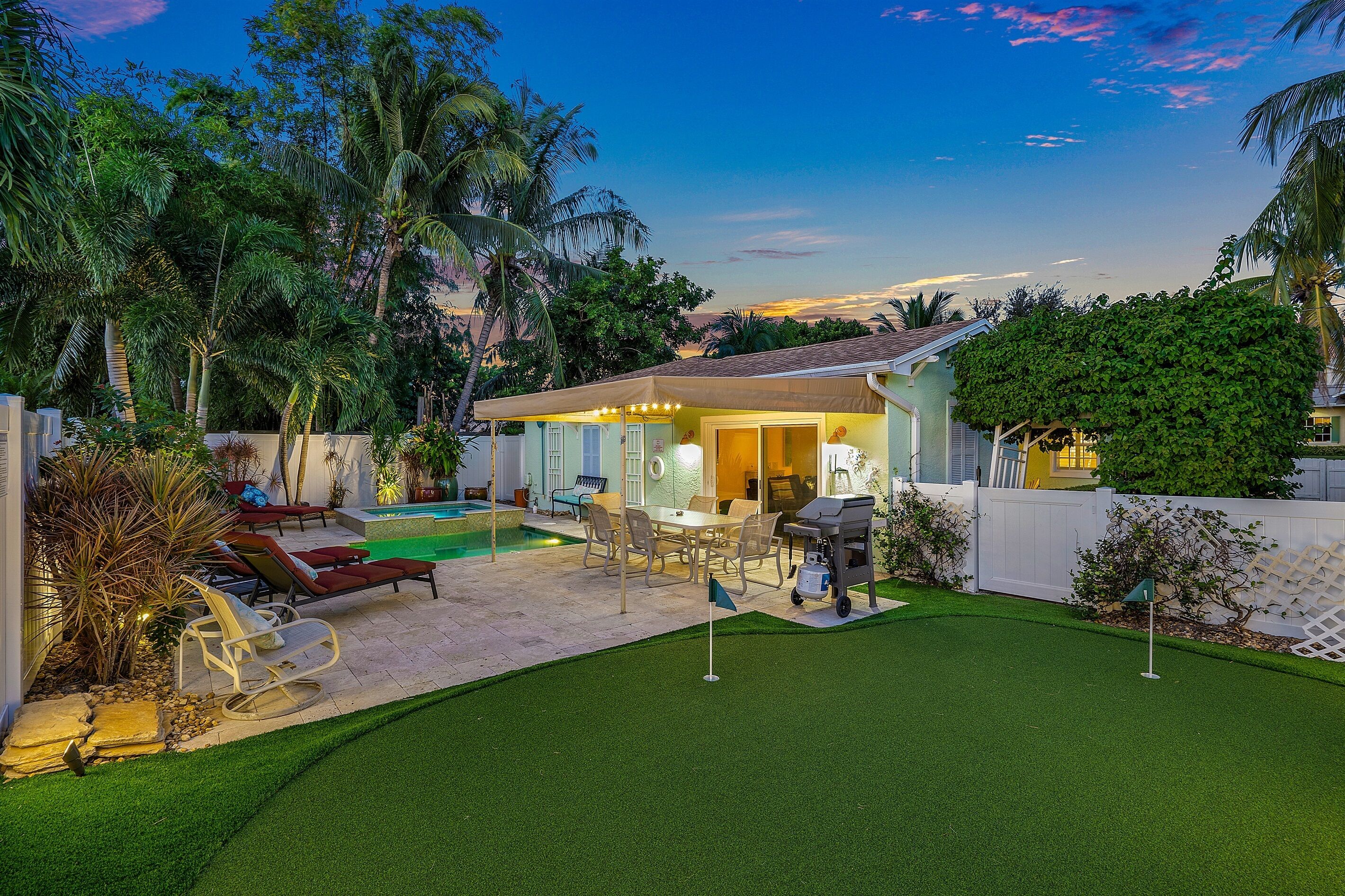 A backyard with a pool, patio furniture, and a barbecue area.