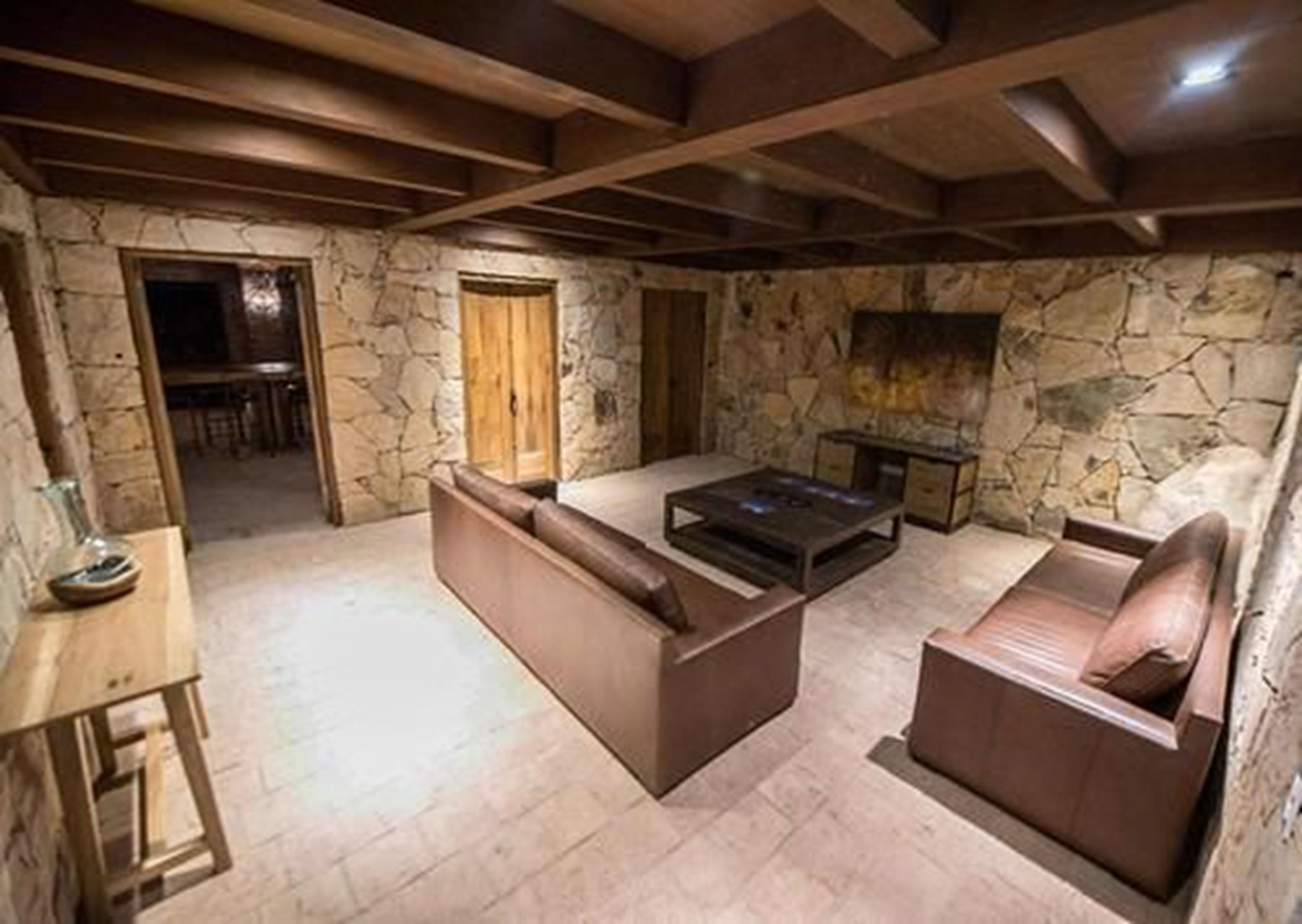 Una sala de estar acogedora con paredes de piedra, una chimenea y techo de madera.