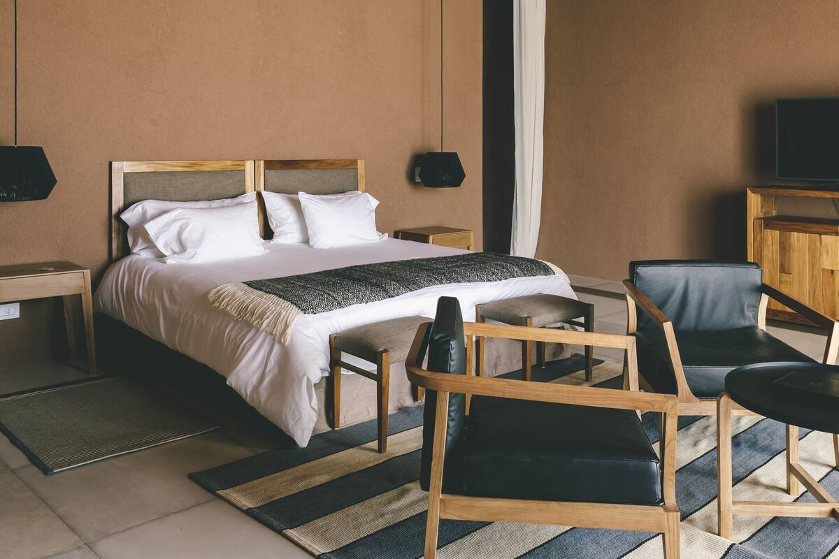 A hotel room with a bed, bedside tables, a TV, a desk, and a chair.