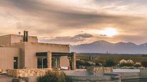 Un edificio moderno con piscina, muros de piedra y vistas a montañas.