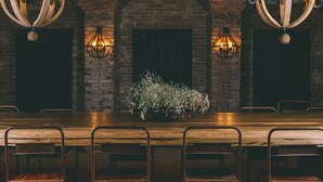 Un restaurante con techo de ladrillo, mesas de madera y candelabros colgantes.