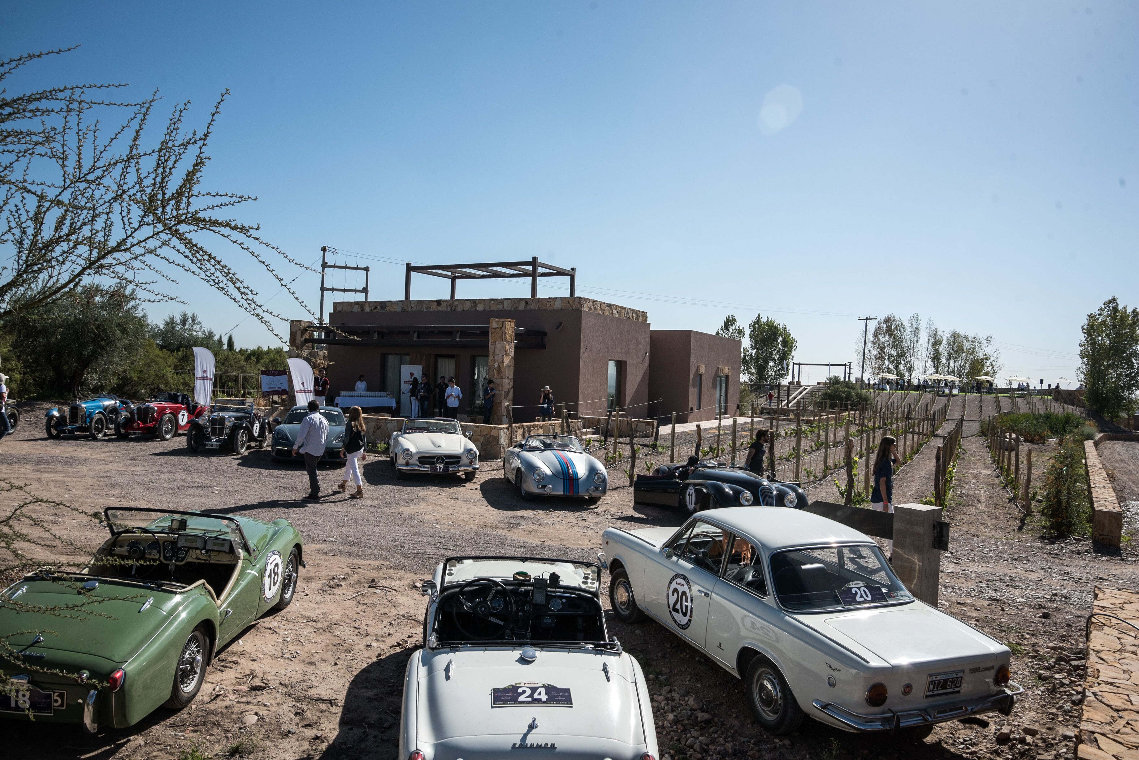 A vintage car show with various classic cars parked on a dirt ground.