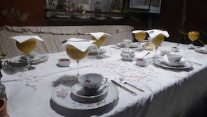 Una mesa dispuesta para una comida, con mantel floral, platos blancos y cristalería.