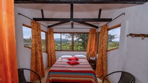 A bedroom with a bed, two chairs, a window, and curtains.
