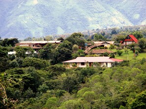 A rural village with traditional houses surrounded by lush greenery and hills in the background. - Hotel Alto de los Andaquies (San Agustin)