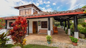 A house with a tiled roof, a covered porch, and a garden with potted plants.