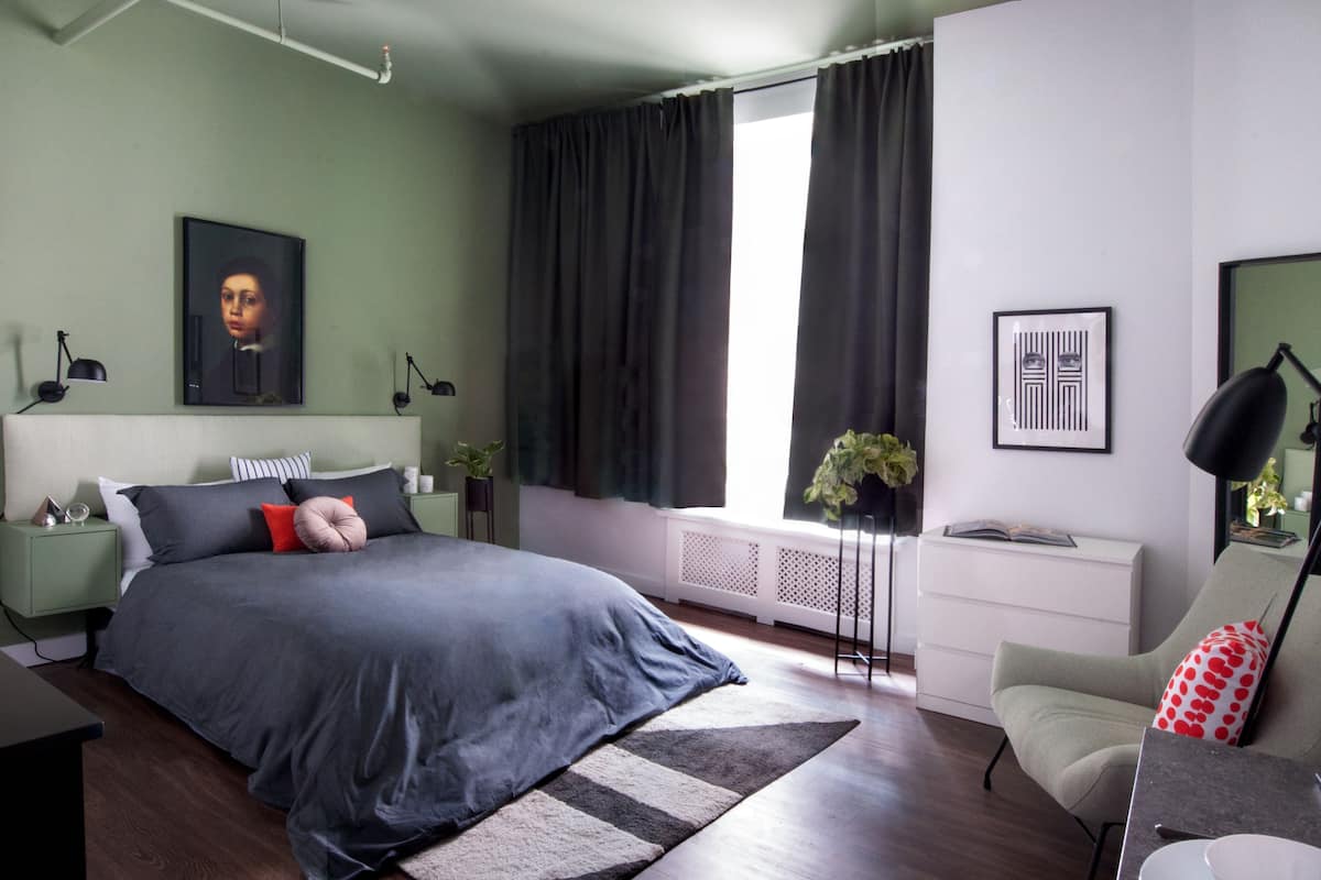 A modern bedroom with a large bed, bedside tables, a desk, and a window with curtains.