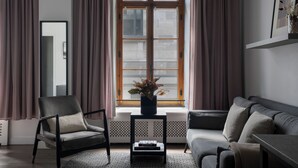 A modern living room with a large window, a sofa, a chair, and a small table with books.