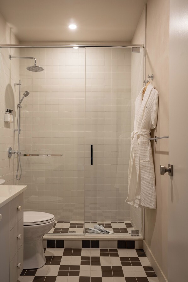 A bathroom with a shower, toilet, and a towel rack.