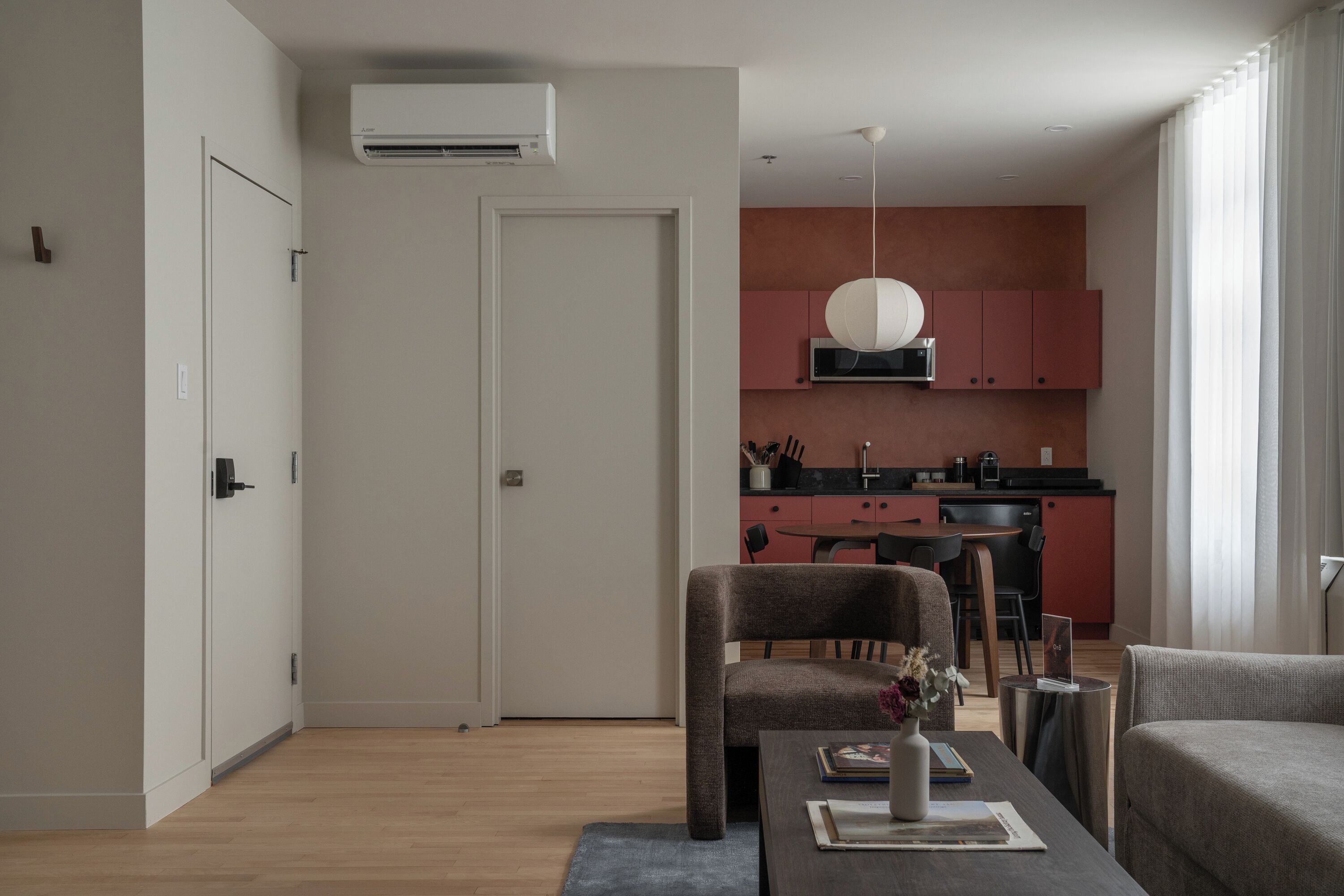 Una sala de estar moderna con una mesa de comedor, un sofá y una cocina al fondo.