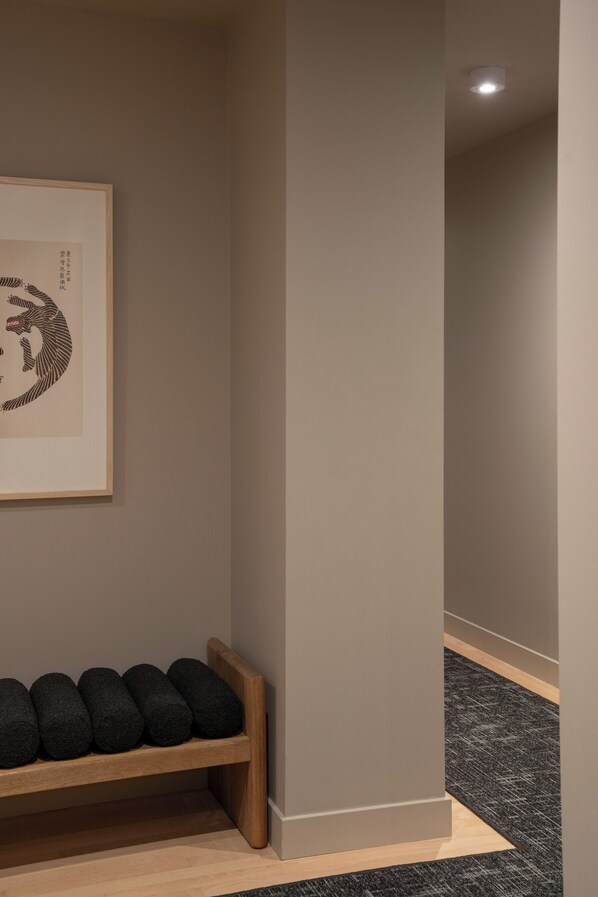 A hallway with a wooden bench, a framed artwork, and a carpeted floor.