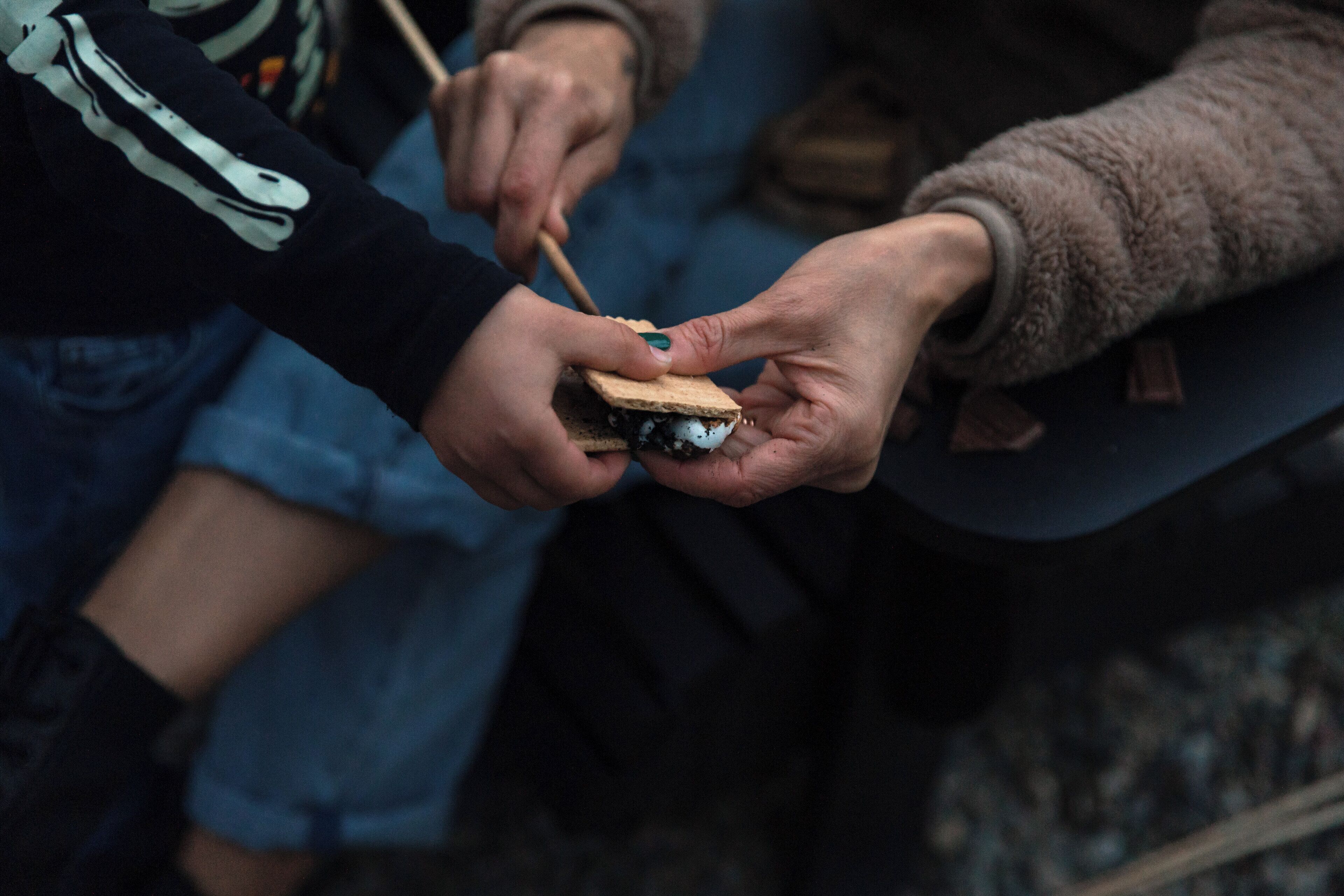 Une personne tenant un sandwich à l’aide d’un bâtonnet en bois.