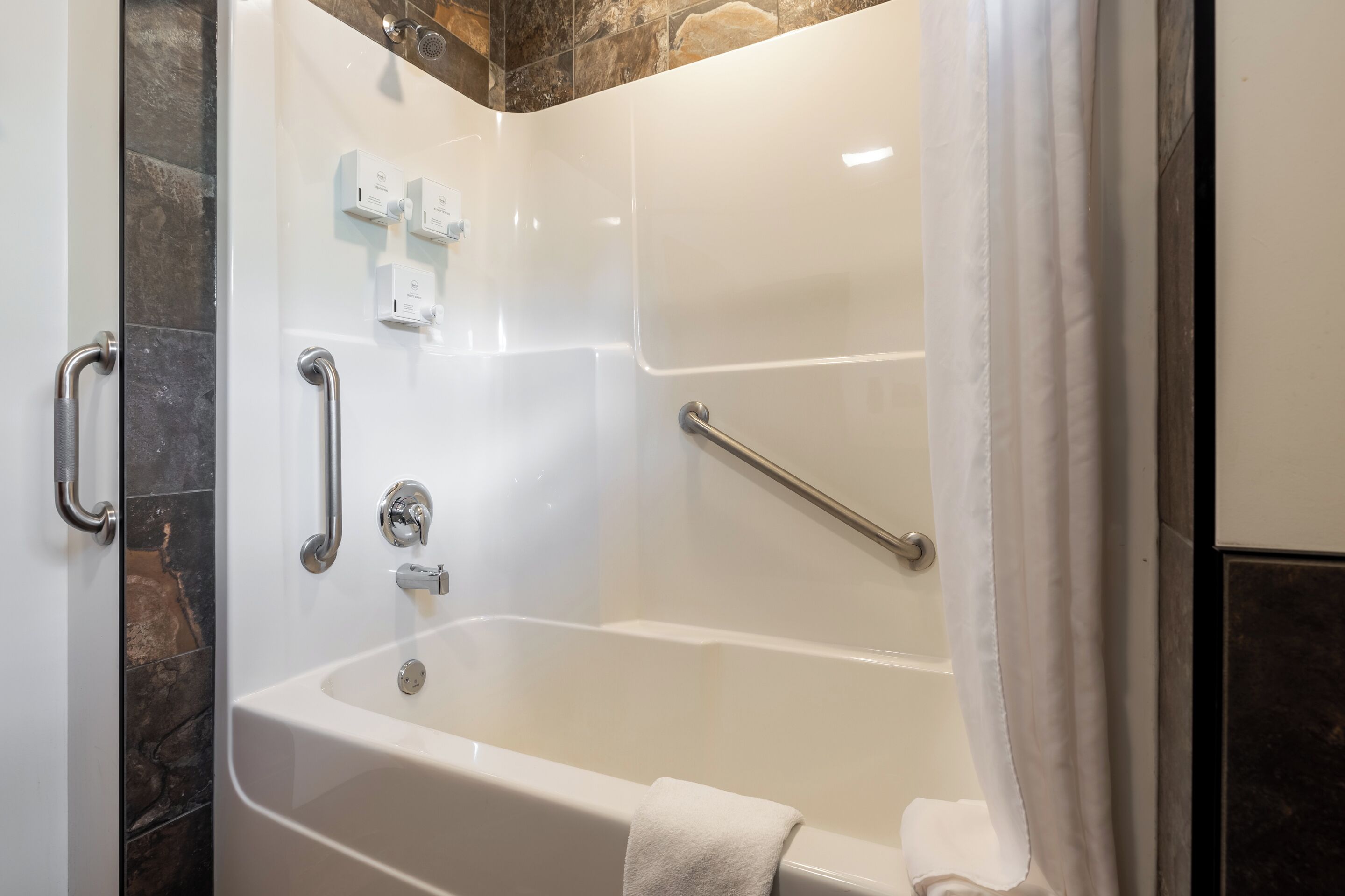Ein modernes Badezimmer mit Badewanne, Haltegriffen und einer Duschkabine.